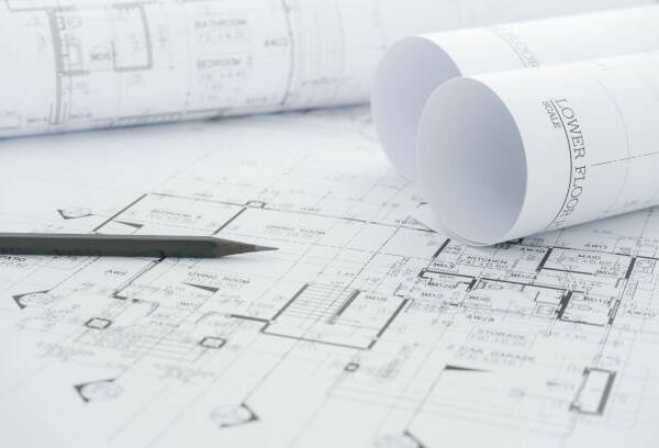 architects workplace - architectural blueprints with measuring tape and black pencil on table.