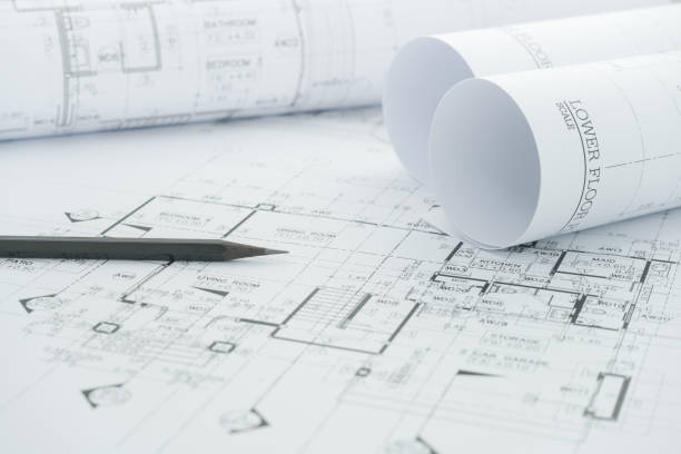 architects workplace - architectural blueprints with measuring tape and black pencil on table.